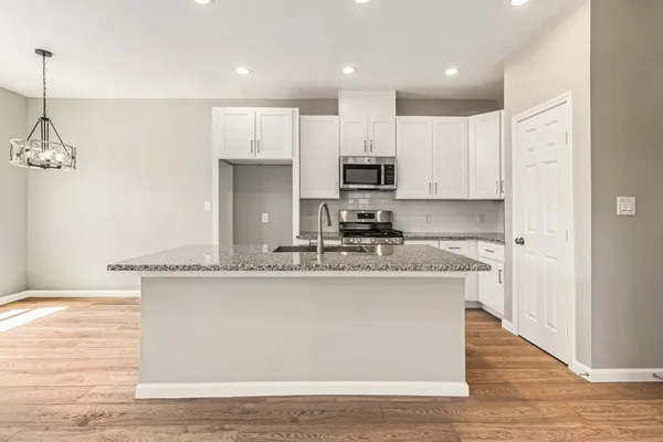 a kitchen with stainless steel appliances granite countertop a sink a stove and a refrigerator