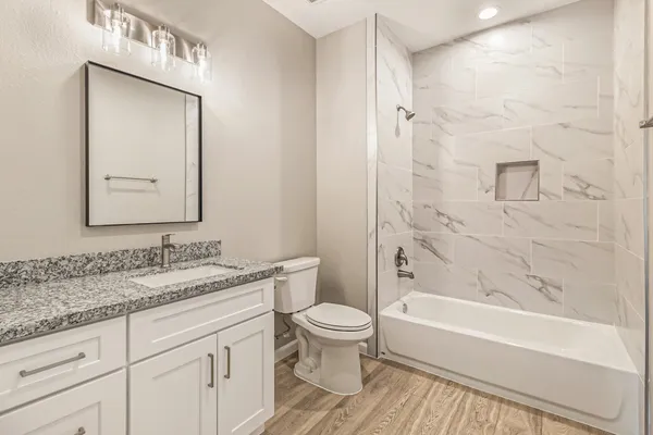 a bathroom with a granite countertop sink a toilet and a bathtub