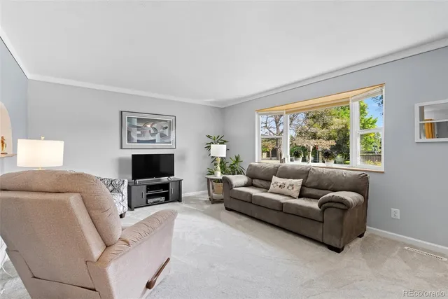 a living room with furniture a large window and a flat screen tv