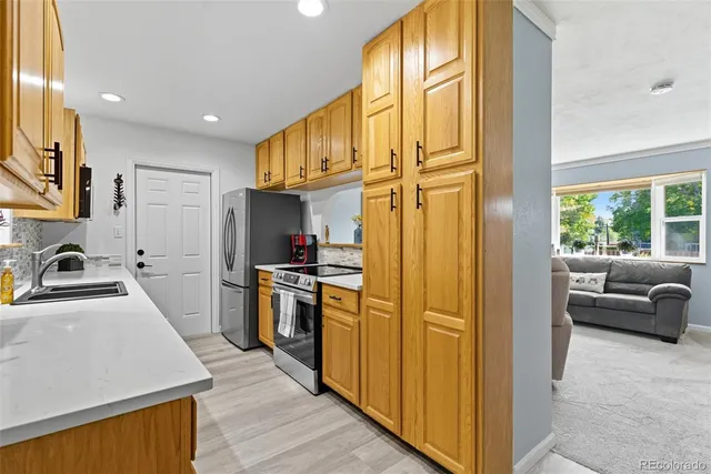 a kitchen with stainless steel appliances granite countertop a refrigerator a sink dishwasher a stove and a dining table with wooden floor