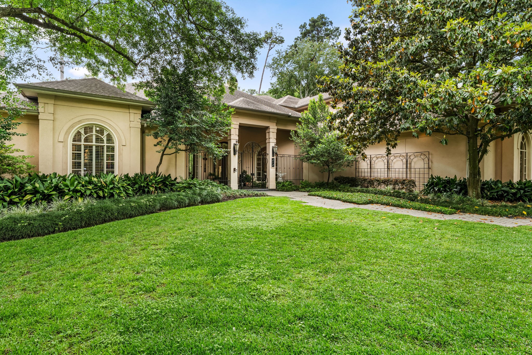 6 Mott Lane Houston, TX 77024 - Photo 5 of 50 Elegant front courtyard framed by mature trees and lush landscaping, offering a private, serene approach to the home.