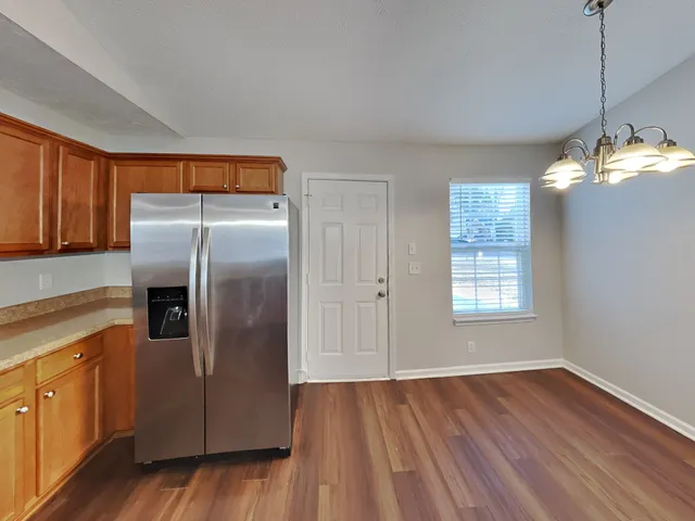 a kitchen with stainless steel appliances granite countertop a refrigerator a sink dishwasher a stove and white countertops with wooden floor