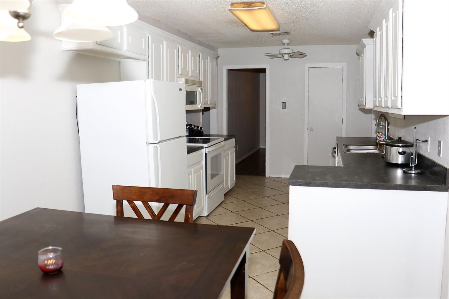 7004 Elkhart Avenue Lubbock, TX 79424 - Photo 16 of 44 a kitchen with stainless steel appliances a refrigerator a sink a stove and white cabinets