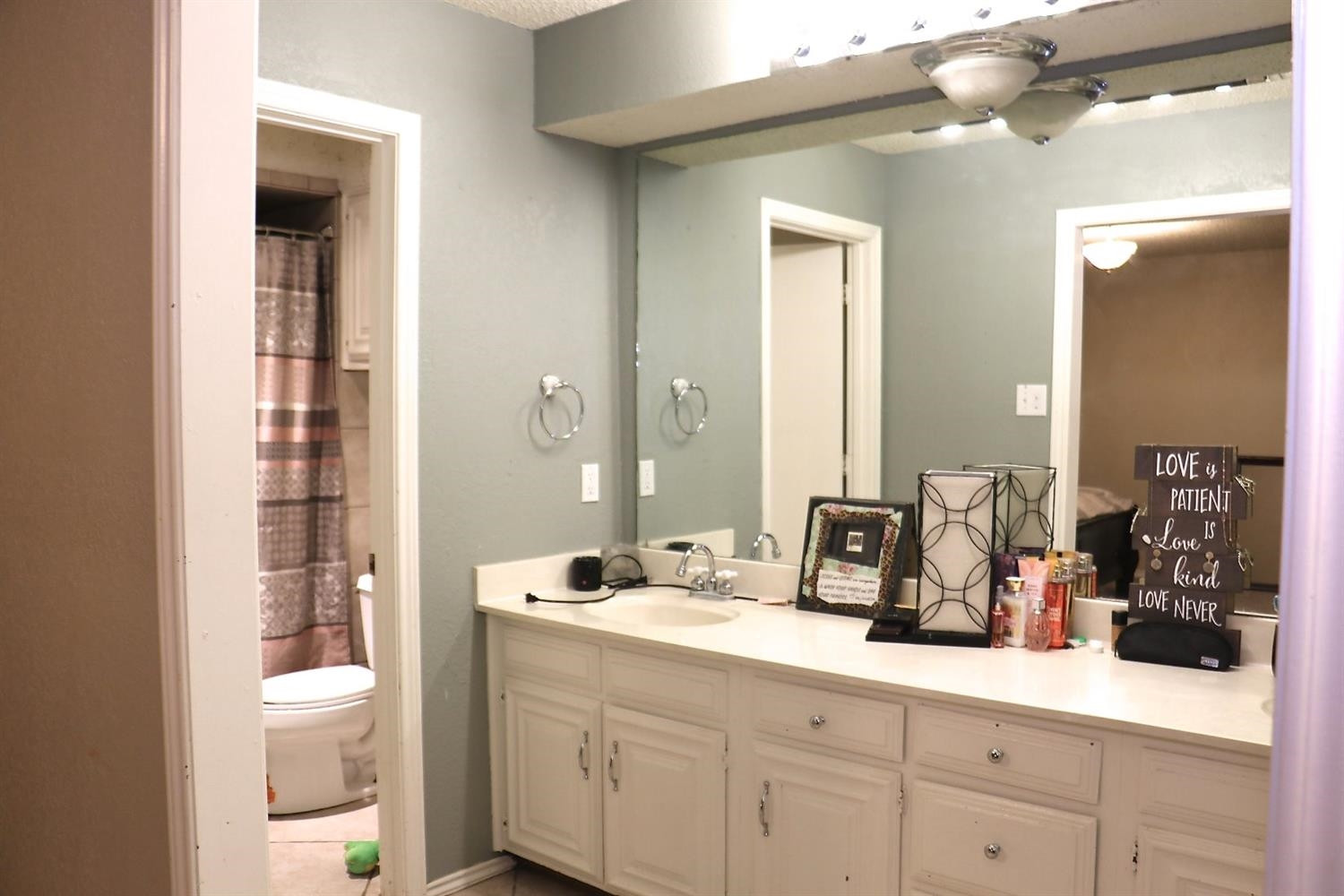 7004 Elkhart Avenue Lubbock, TX 79424 - Photo 9 of 44 a bathroom with a granite countertop sink a toilet and a large mirror