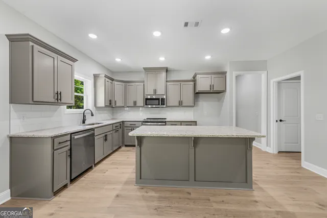 a kitchen with granite countertop a sink cabinets stainless steel appliances and a window