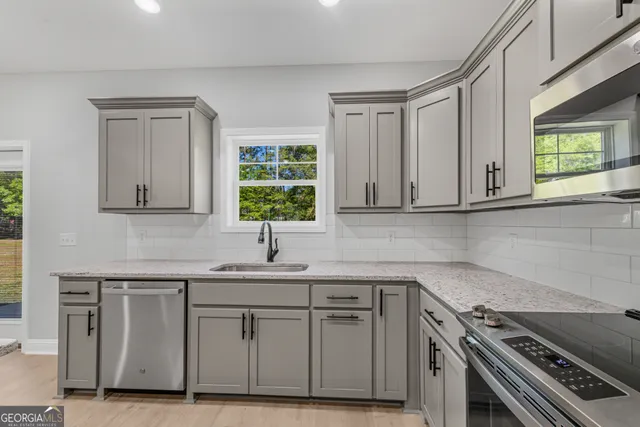 a kitchen with granite countertop white cabinets and stainless steel appliances