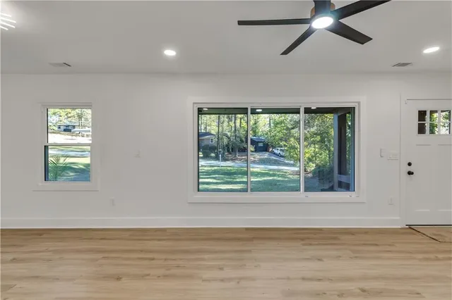 a view of an empty room with wooden floor and a window