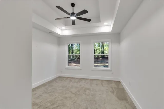 an empty room with a ceiling fan and windows