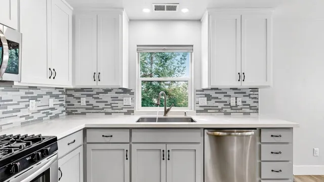 a kitchen with granite countertop a sink cabinets window and stainless steel appliances