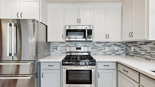 a kitchen with stainless steel appliances white cabinets a stove top oven and refrigerator