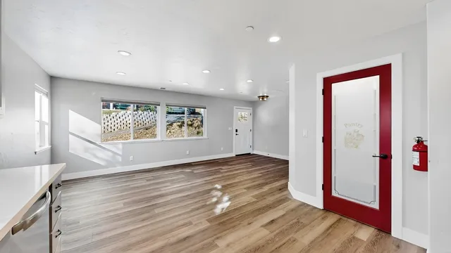 a view of an empty room with wooden floor and a window