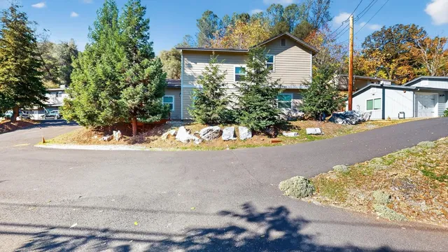 a view of a house with a yard and large tree