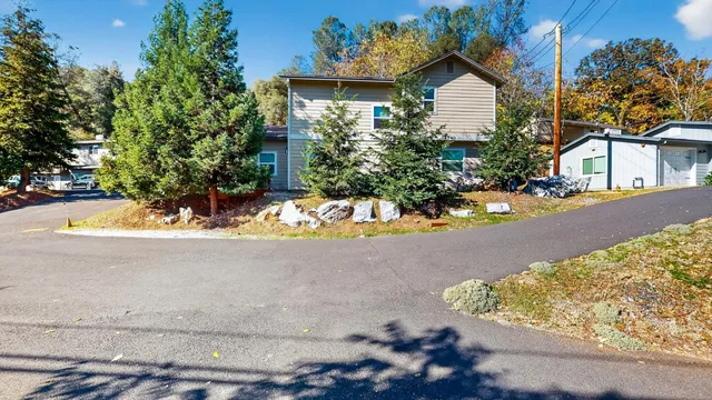 a view of a house with a yard and large tree