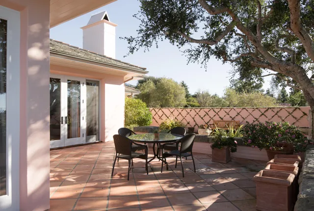 a patio with table and chairs and potted plants