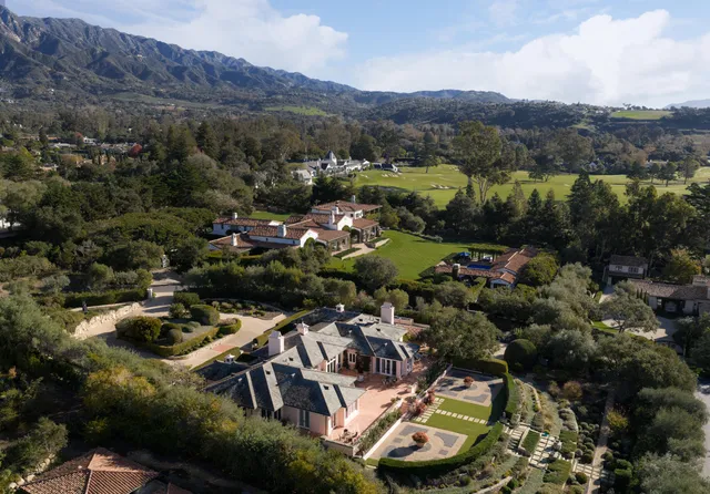 an aerial view of a house with a yard and large trees