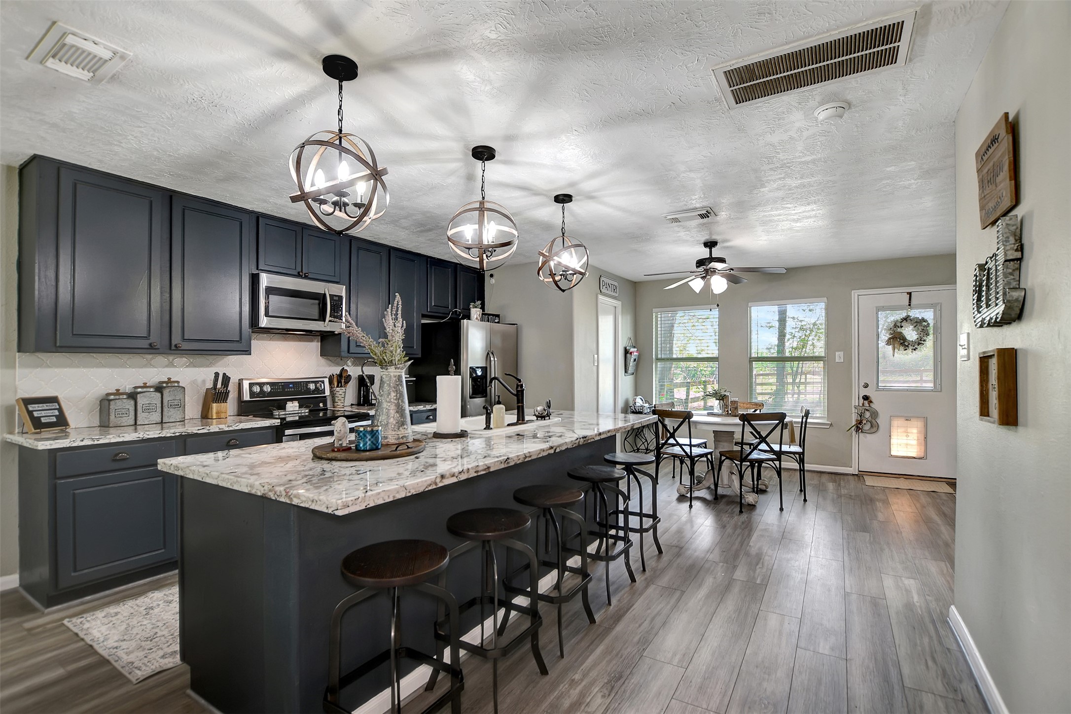 25401 Hunting Trail Magnolia, TX 77355 - Photo 12 of 50 a kitchen with cabinets appliances wooden floor dining table and chairs