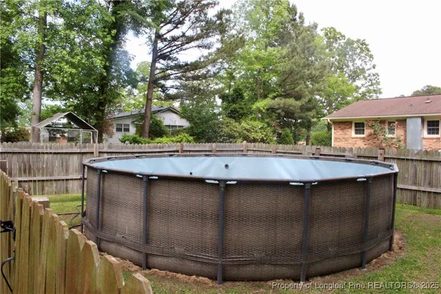 a backyard of a house with wooden fence and large trees