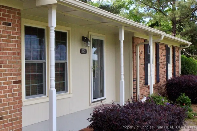 a view of yellow house with potted plants and a table and chair