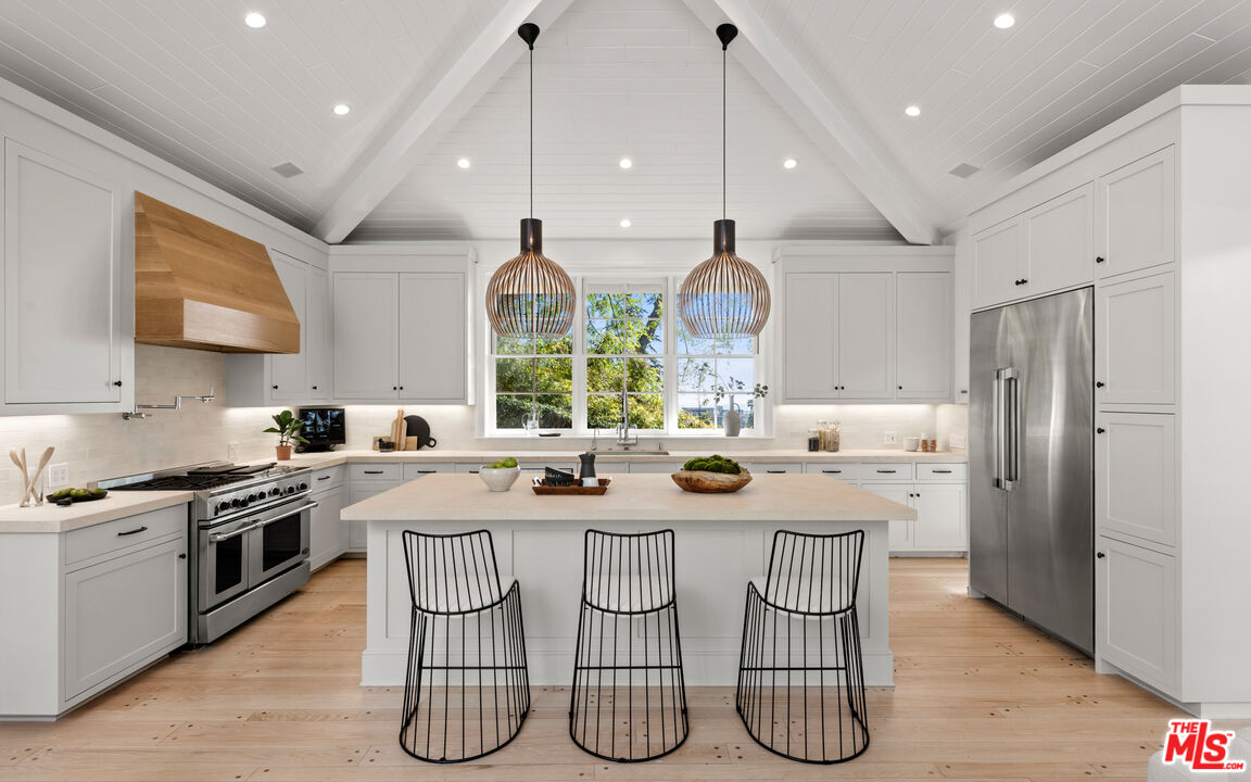a kitchen with stainless steel appliances a table chairs and wooden floor