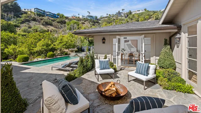 a view of a patio with table and chairs potted plants and floor to ceiling window