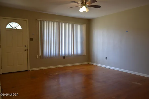 an empty room with chandelier fan and windows