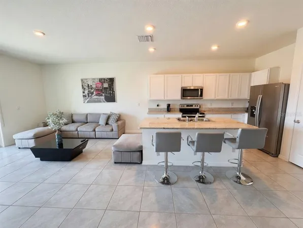a living room with furniture and a refrigerator
