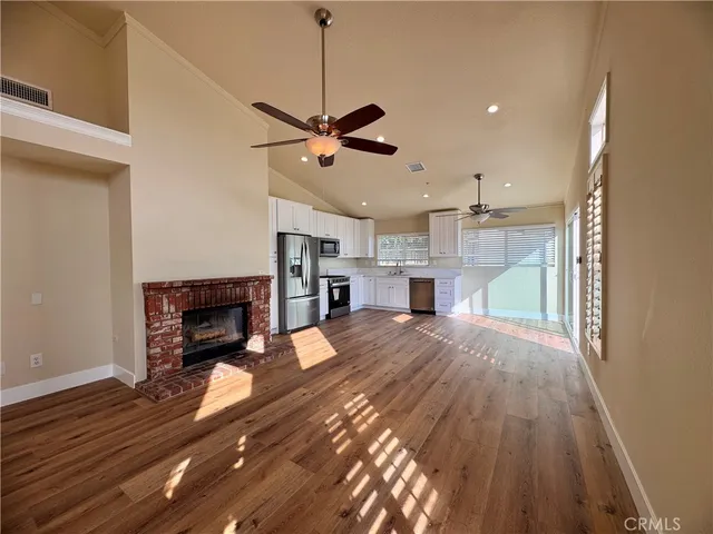a view of a livingroom with a fireplace a ceiling fan and wooden floor