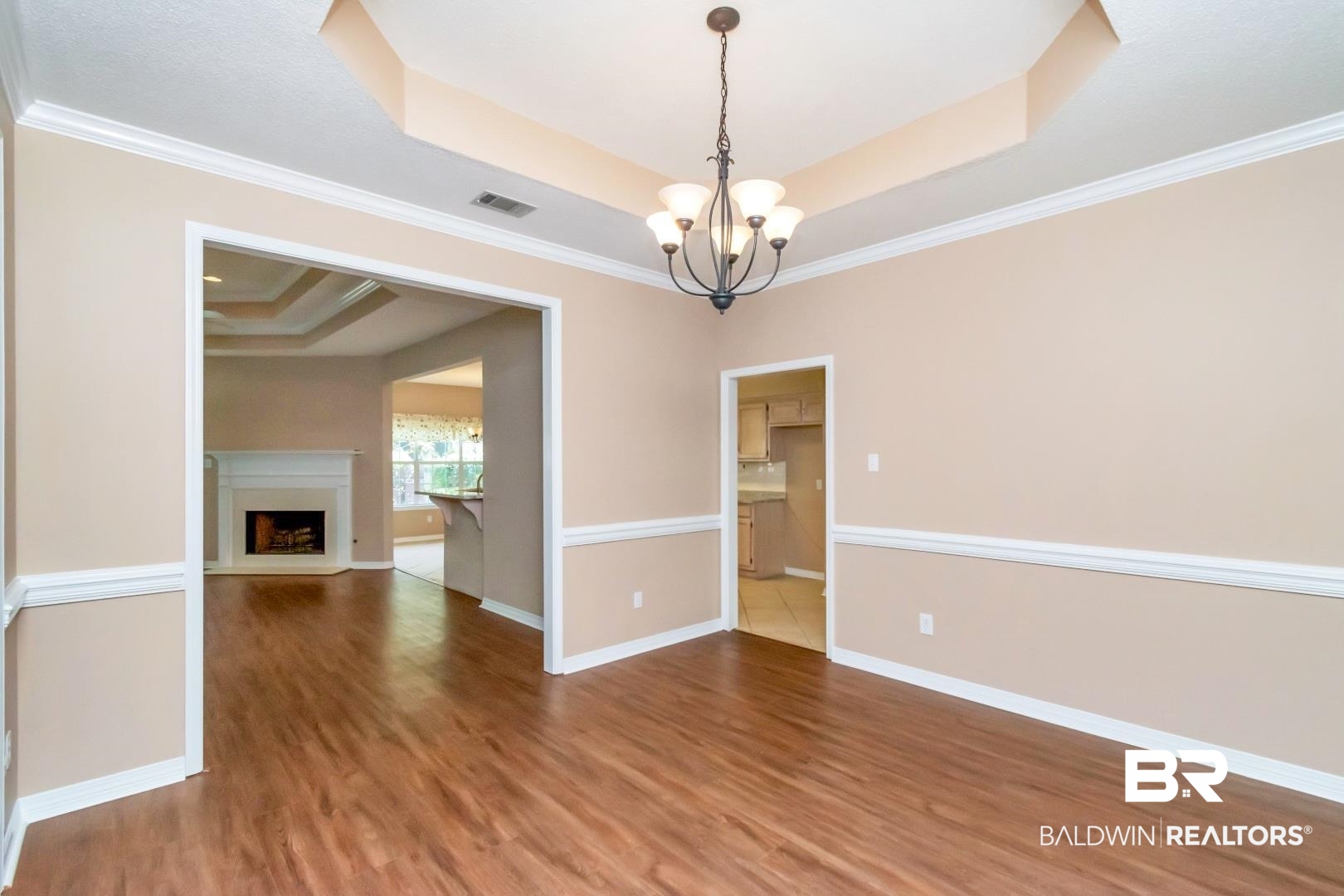 6117 Lennox Place Mobile, AL 36693 - Photo 6 of 39 Unfurnished room with visible vents, wood finished floors, a raised ceiling, baseboards, and an inviting chandelier