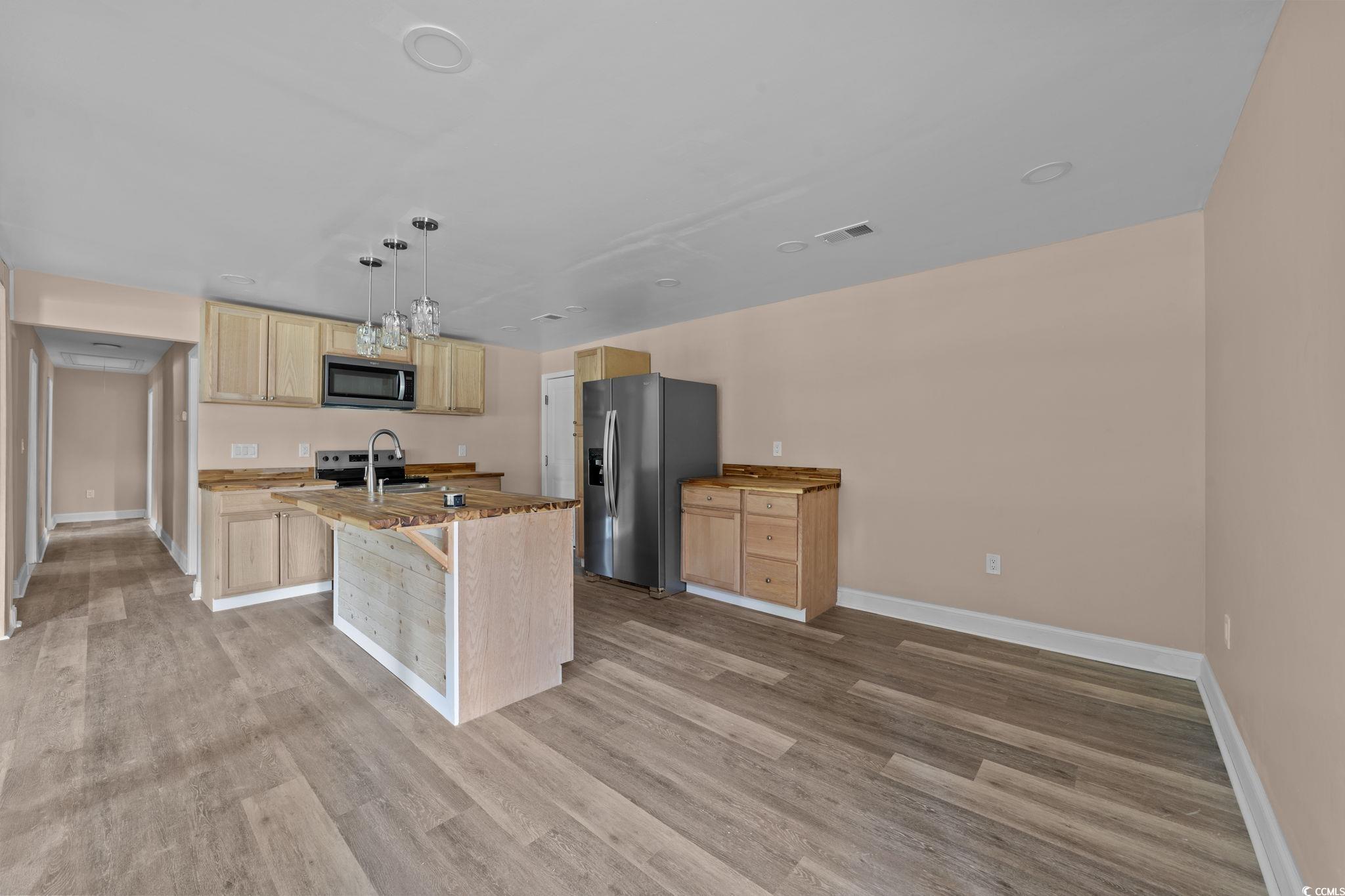 1821 Hawkins Street Georgetown, SC 29440 - Photo 22 of 40 Kitchen featuring light brown cabinetry, light wood finished floors, appliances with stainless steel finishes, and a kitchen island with sink