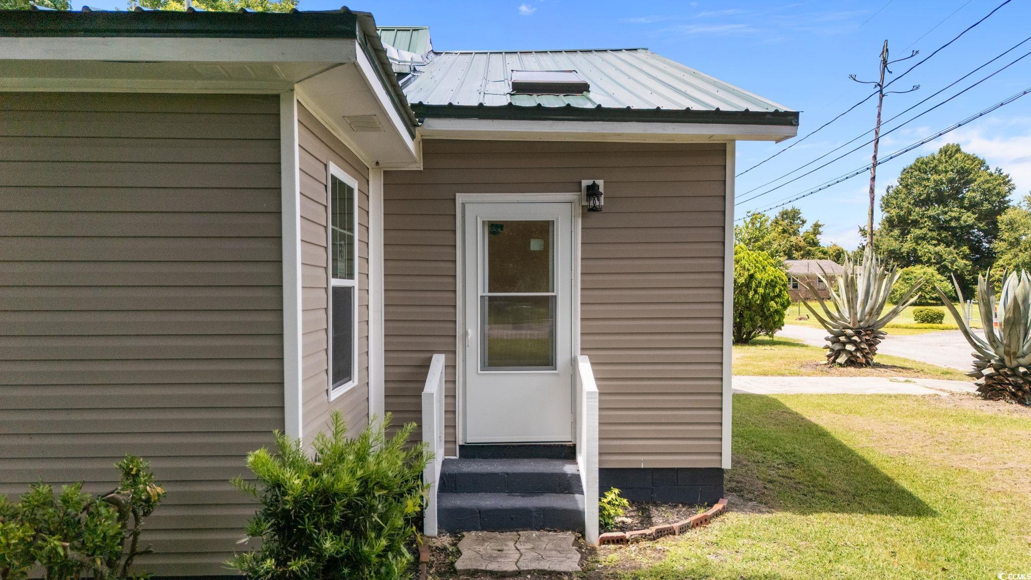 1821 Hawkins Street Georgetown, SC 29440 - Photo 6 of 40 View of exterior entry with a lawn and a metal roof