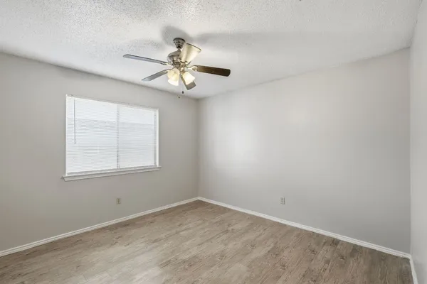 an empty room with a window and a fan