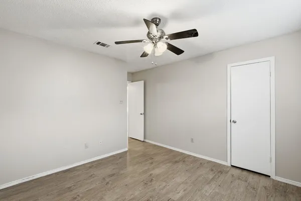 an empty room with wooden floor and a ceiling fan