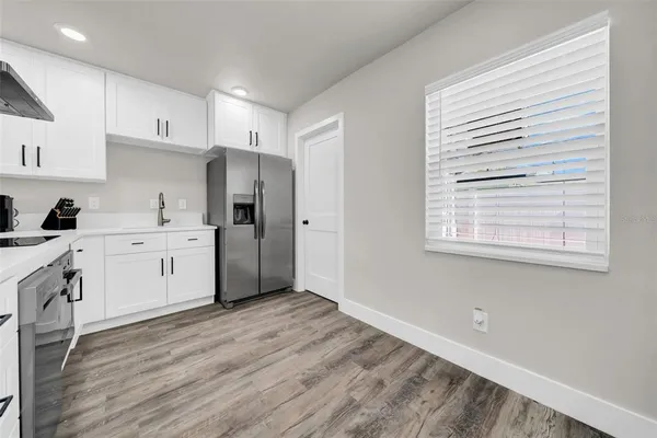 a kitchen with white cabinets and wooden floor