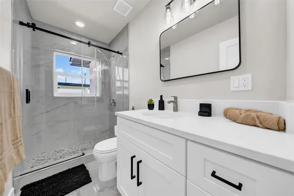 a bathroom with a sink a toilet and shower