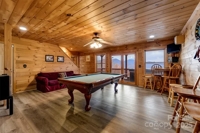 a room with furniture pool table wooden floor and windows