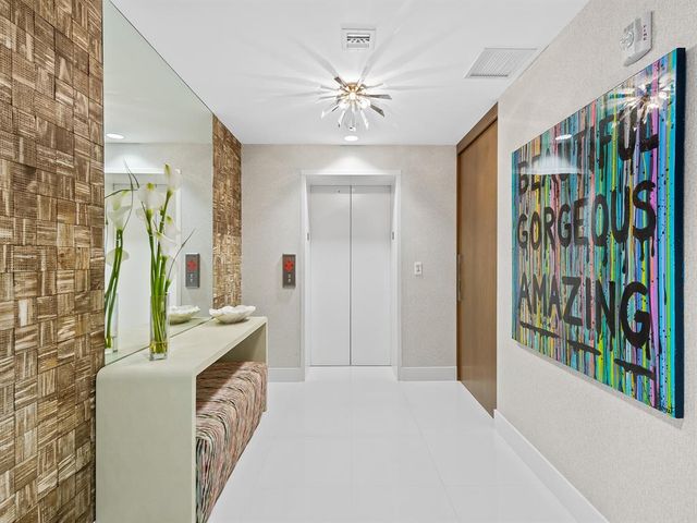 a view of a hallway with furniture and a chandelier