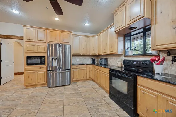 a kitchen with granite countertop a refrigerator and a stove top oven