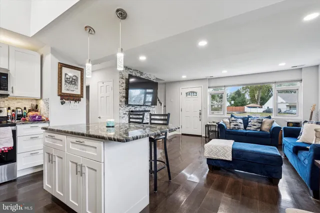 a kitchen that has cabinets a stove a sink and a dining table with chairs
