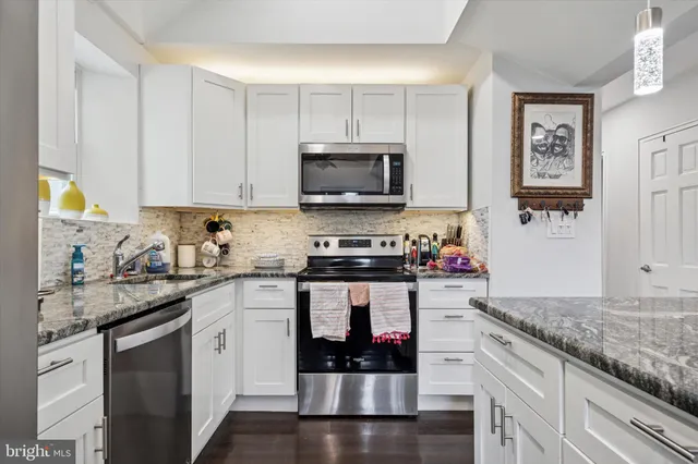 a kitchen with stainless steel appliances granite countertop a stove a sink and a microwave