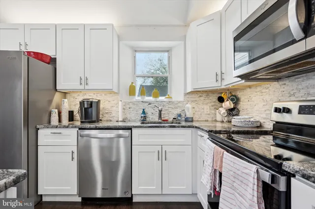 a kitchen with granite countertop a sink stainless steel appliances and cabinets
