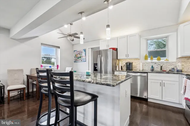 a kitchen with stainless steel appliances granite countertop a dining table and chairs
