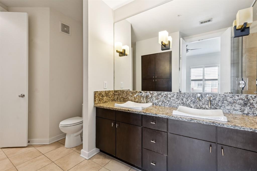 2950 McKinney Avenue, Unit 424 Dallas, TX 75204 - Photo 13 of 25 a bathroom with a granite countertop sink a toilet and a mirror