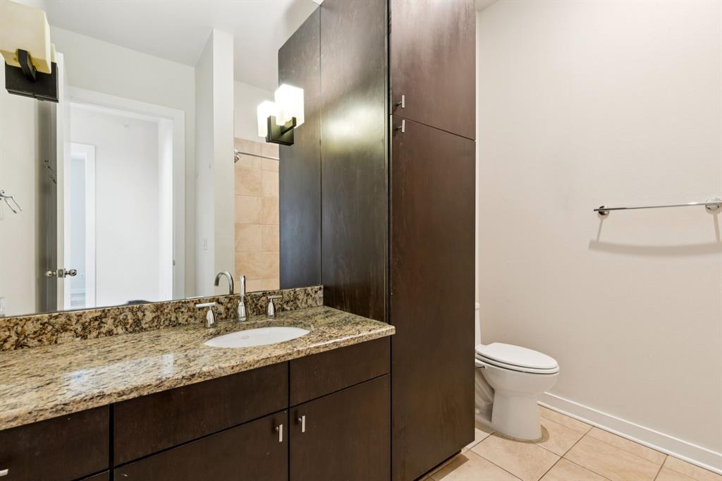 2950 McKinney Avenue, Unit 424 Dallas, TX 75204 - Photo 20 of 25 a bathroom with a granite countertop sink a toilet and a mirror