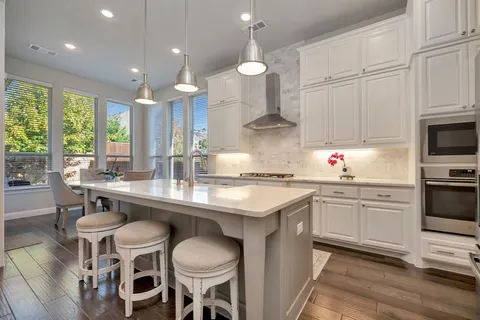 a kitchen with granite countertop white cabinets stainless steel appliances and dining table