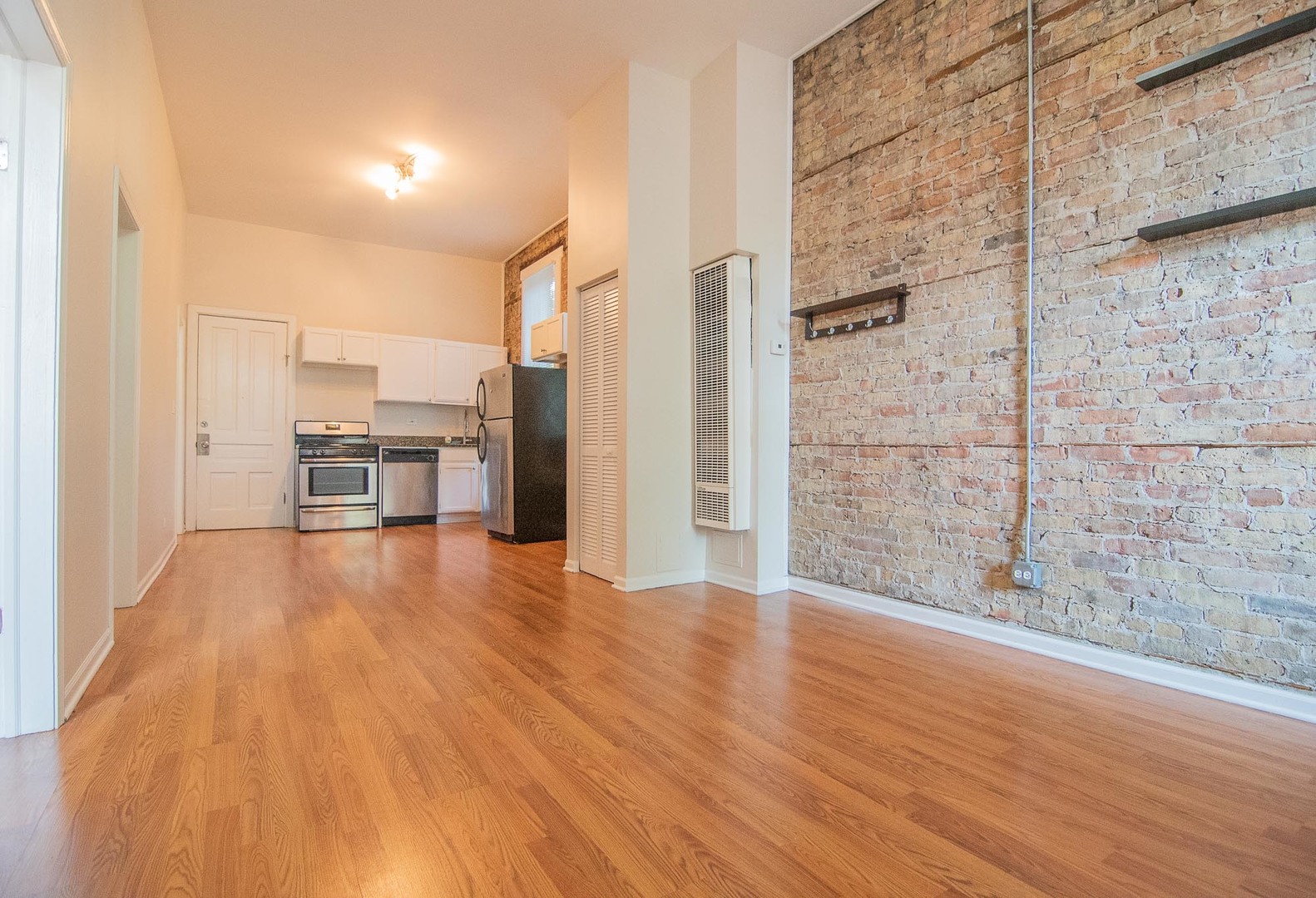 1475 West Huron Street, Unit 1R Chicago, IL 60642 - Photo 2 of 8 a view of empty room with wooden floor and fireplace