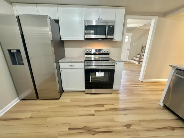 a kitchen with stainless steel appliances a refrigerator stove and wooden floor