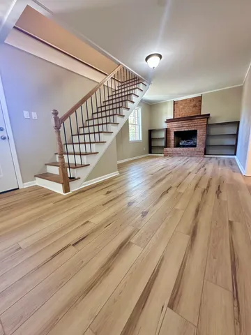 an empty room with wooden floor fireplace and windows