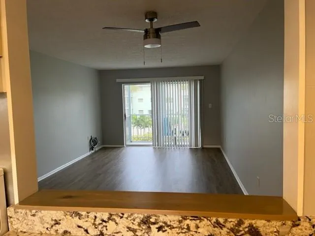 a view of an empty room with a window and wooden floor