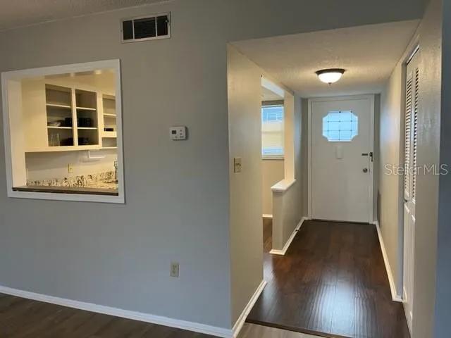 a view of a hallway with wooden floor and a bathroom