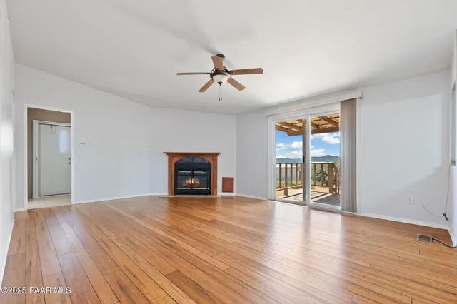 a view of empty room with a fireplace and wooden floor